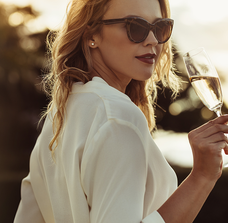 Woman with sunglasses sipping champagne
